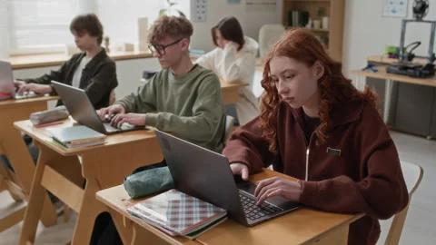 Group of Teenagers Using Laptops While Studying at Their Desks Stock Footage 335700267
