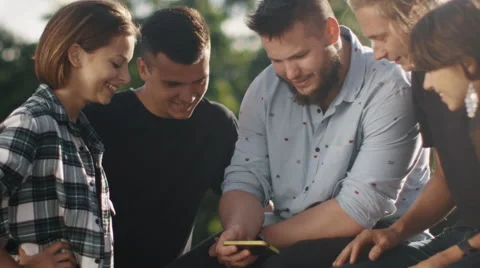 Group of Teenagers Using Mobile Phone for Entertainment Outdoors Stock Footage