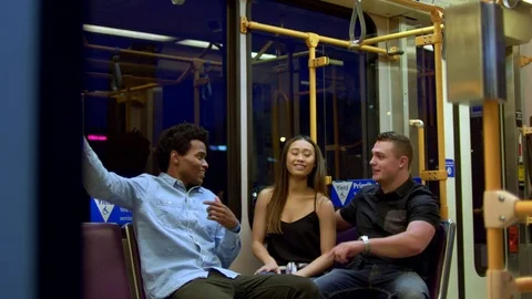 Group of teens laugh while riding a train in the city at night. Stock Footage 77741847
