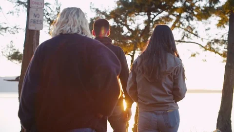 A group of teens walk up a hill in the sunset - lens flares Stock Footage 87533105