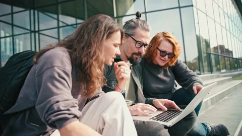Group of three friends discussing the project and looking at a laptop screen Stock Footage 218103548