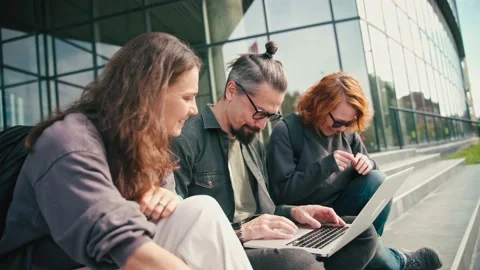 Group of three friends discussing the project and looking at a laptop screen Stock Footage 219852194