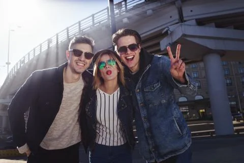 A group of three friends having fun and laughing at street.