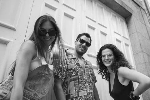 A group of three friends having fun and laughing on a bench in the street Stock Photos