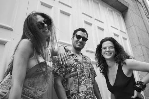 A group of three friends having fun and laughing on a bench in the street Stock Photos