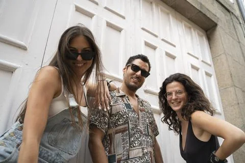 A group of three friends having fun and laughing on a bench in the street Stock Photos