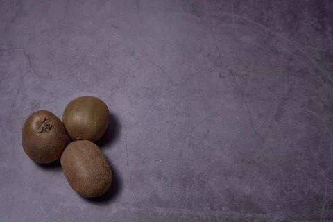 Group of three kiwis on stone floor Stock Photos
