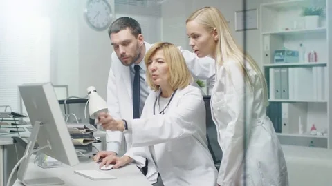 Group of Three Medical Specialists Solving Problems at the Desktop Computer.  Stock Footage 70428904