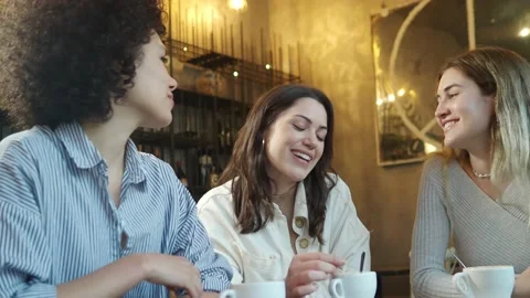 Group of three multi-ethnic female friends chatting and drinking coffee Stock Footage 218978311