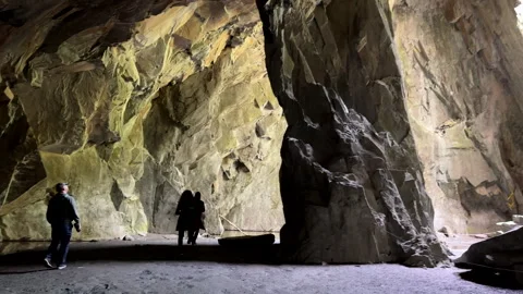 Group of three people exploring abandoned quarry, inside of Cathedral Cave. 動画素材 309212947