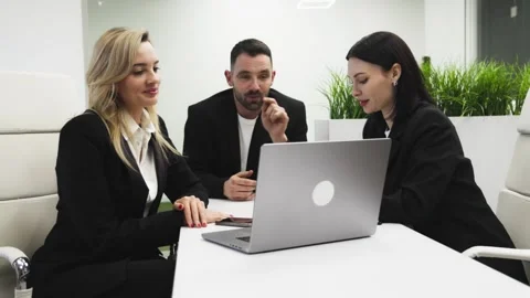 Group of three professionals engaged in a collaborative discussion around a Stock Footage 334795119