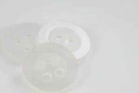 Group of three small white round plastic buttons on a white background. Stock Photos