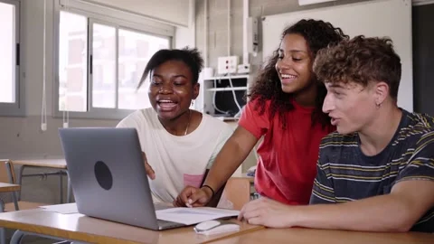 Group of three smiling multicultural teenage students looking at the laptop Stock Footage 239471960