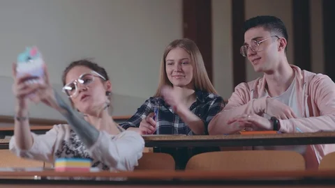 Group of three students in classroom take photos on smartphone 库存影片 88807669