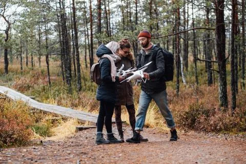 Group of three students with quadcopter in autumn forest Stock Photos