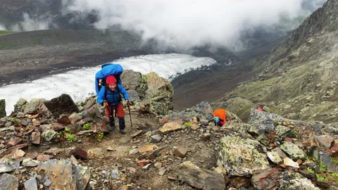 A group of three tourists climbs up a mountain path Video stock 158159229