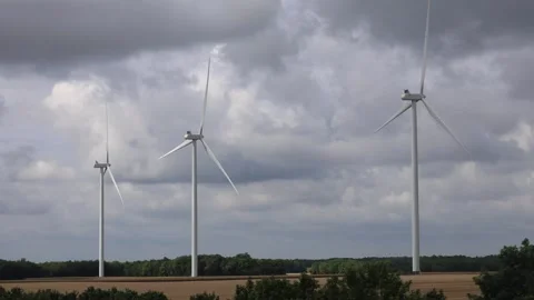 A Group Of Three Wind Turbines In A Field Spinning On A Cloudy Day Stock Footage 307653447