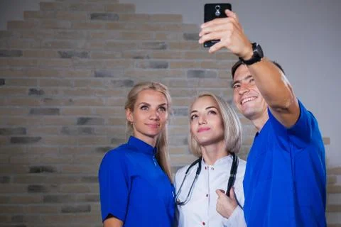 Group of three young doctors making selfie in white and blue uniform 库存照片