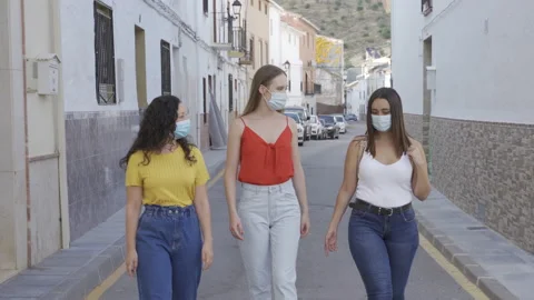Group of three young female walking down the street speaking fun wearing a face Stock Footage 142891069