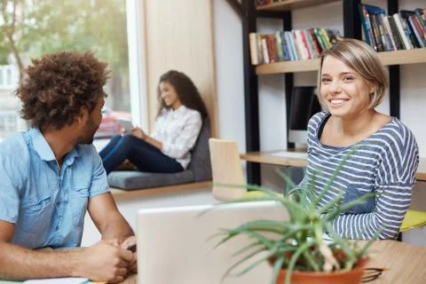 Group of three young good-looking multi-ethnic students sitting in university Fotos Stock