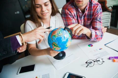 Group of three young people with globe choose country to travel to. Stockfoto's
