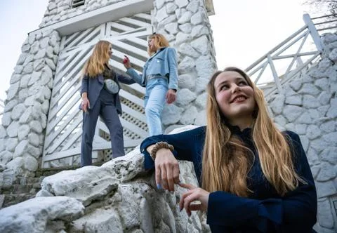 Group of three young Stylish nice girls in pantsuit costumes sitting on a stairs Stock Photos