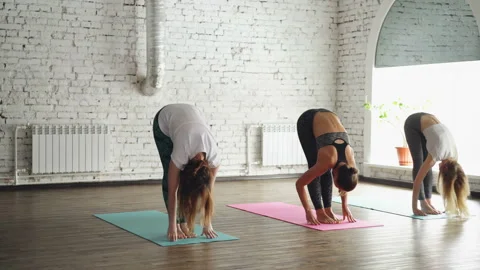 Group of three young women is practicing yoga doing elements of Sun Salutation Stock Footage 89064899