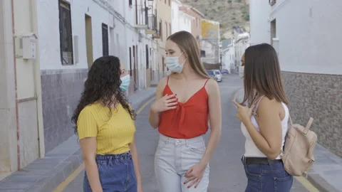 Group of three young women talking in the street with a face mask Stock Footage 143399093