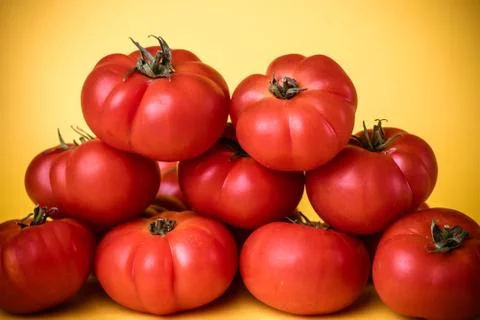 Group of tomatoes in pyramid with yellow background. Stock Photos