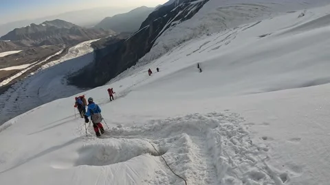 A group of tourists in a bunch descends down a snow-covered path Vídeos de archivo 208437736