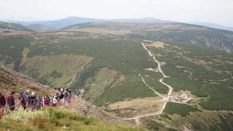 Group of tourists climbs steep mountain path with safety nets while panoramic vi Stock Footage 315940516