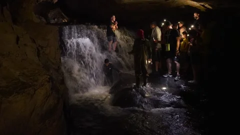 Group of tourists exploring underground waterfall in Jumandy Caves Vídeos de archivo 334934693