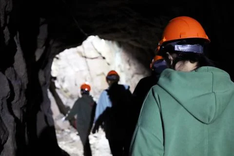 A group of tourists in helmets in a cave Stock Photos