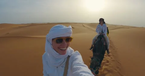 Group of tourists journey through the expansive Sahara Desert, riding camels  Vidéo 324874231