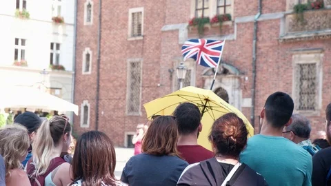 Group Of Tourists Standing on a Central Square of Old City With Flag of England Video stock 114983789
