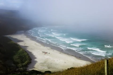 Group of Tourists Walking on the Beach During Foggy Weather Stock Photos