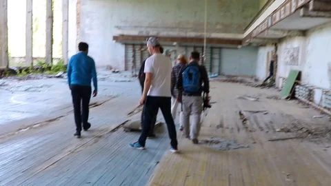 Group of tourists walking through the ruined school gym of town of pripyat. M Stock Footage 129347366