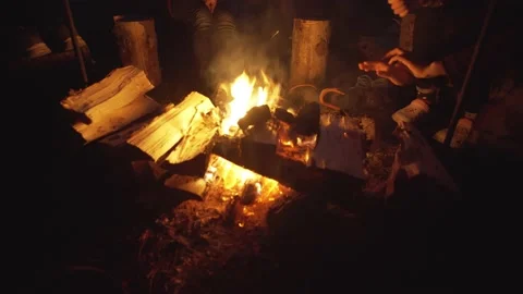 A group of tourists warms up by the fire, dries their shoes at night  Video stock 162876405