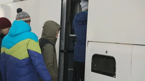 Group of tourists in winter clothes one by one, enter the white bus to go to Stock Footage 64295322