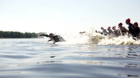 A group of triathletes run into a river to complete the triathlon distance. Stock Footage 277333848