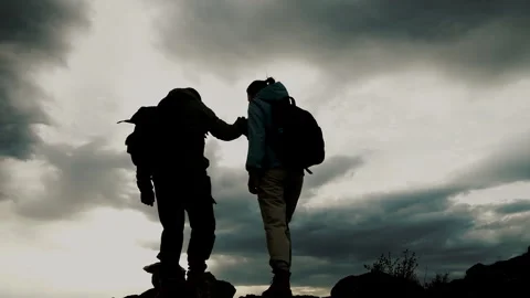 A group of two tourists lend a helping hand by climbing rocks. Stock Footage 275574116
