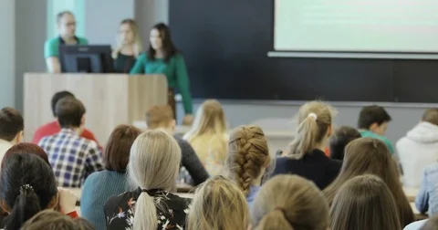 Group of university students sitting at their desks in auditorium and listening Vídeo Stock 85451197