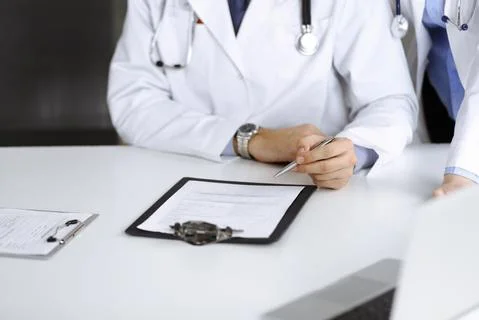 Group of unknown doctors are sitting at the desk and discussing problems or Stock Photos