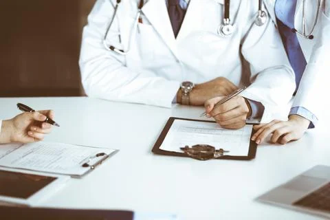 Group of unknown doctors are sitting at the desk and discussing problems or Stock Photos