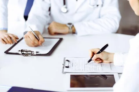 Group of unknown doctors are sitting at the desk and discussing problems or 스톡 사진