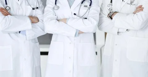 Group of unknown doctors standing as a team with arms crossed in hospital office Stock Photos