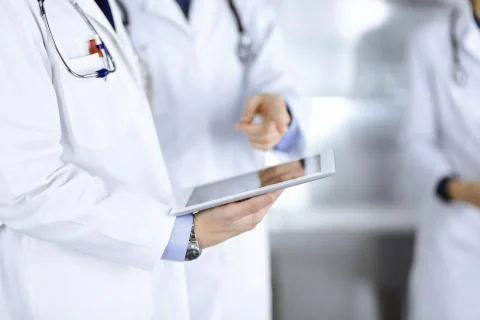 Group of unknown doctors use a computer tablet to check up some medical names Stockfoto's