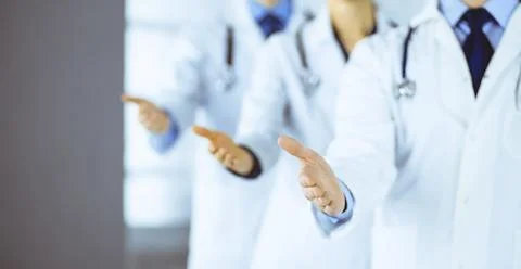 Group of unknown modern doctors stand as a team with open hands in a hospital Stockfoto's