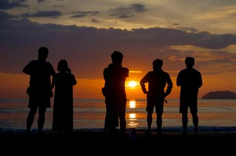 Group of unknown people watching sunset at the beach Stock Photos