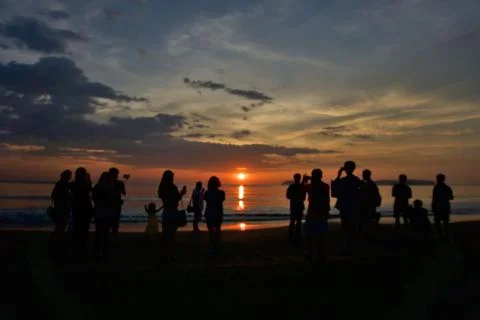 Group of unknown people watching sunset at the beach Stock Photos